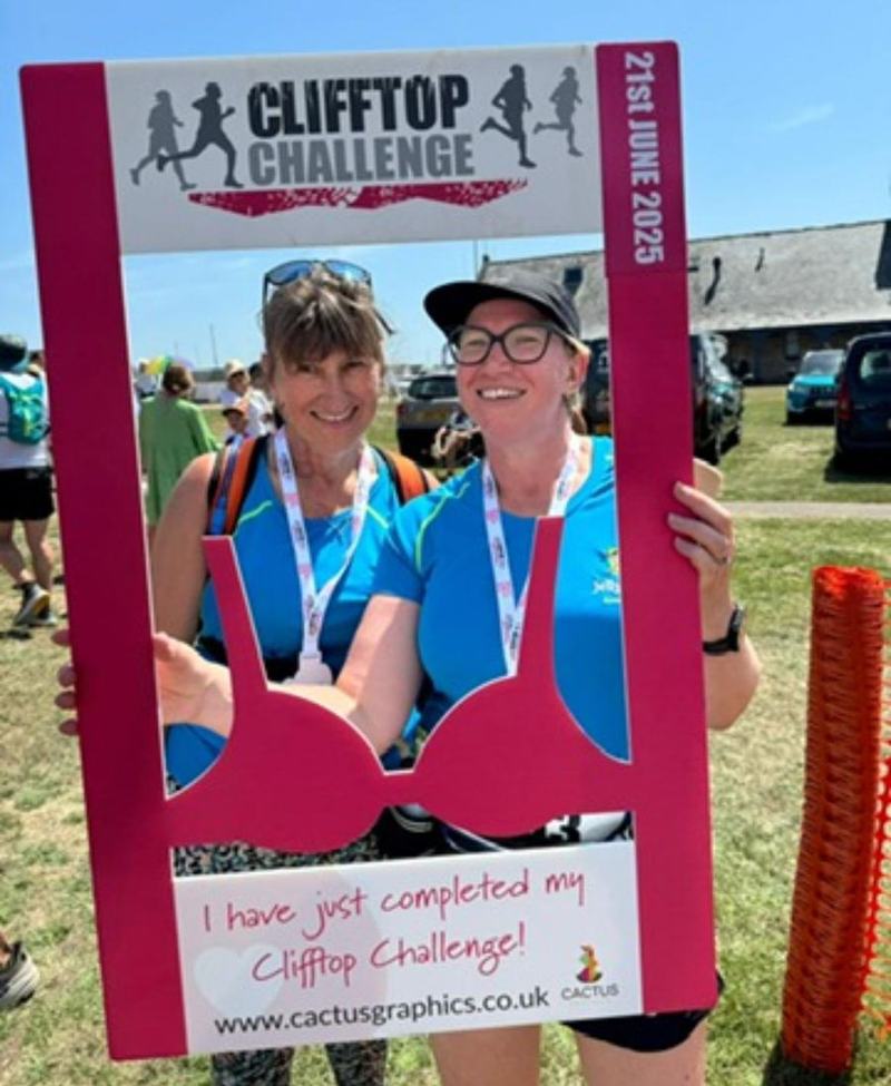 Two Jelly Legs members with their medals in the Clifftop Challenge finish photo frame